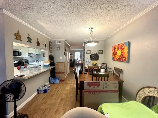 dining room featuring hardwood / wood-style floors, a textured ceiling, and ornamental molding