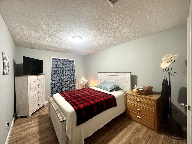 bedroom with a textured ceiling and dark hardwood / wood-style floors