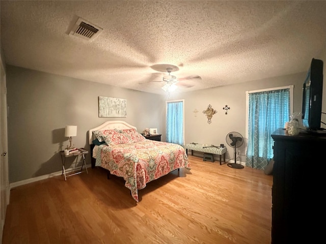 bedroom with hardwood / wood-style floors, a textured ceiling, and ceiling fan