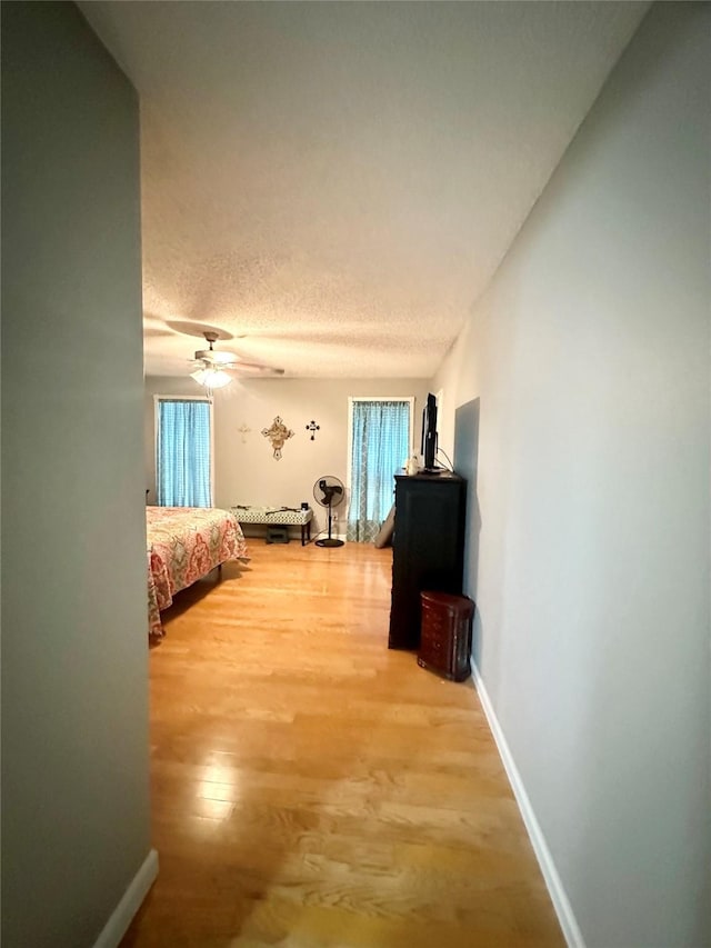 hallway with a textured ceiling and hardwood / wood-style flooring