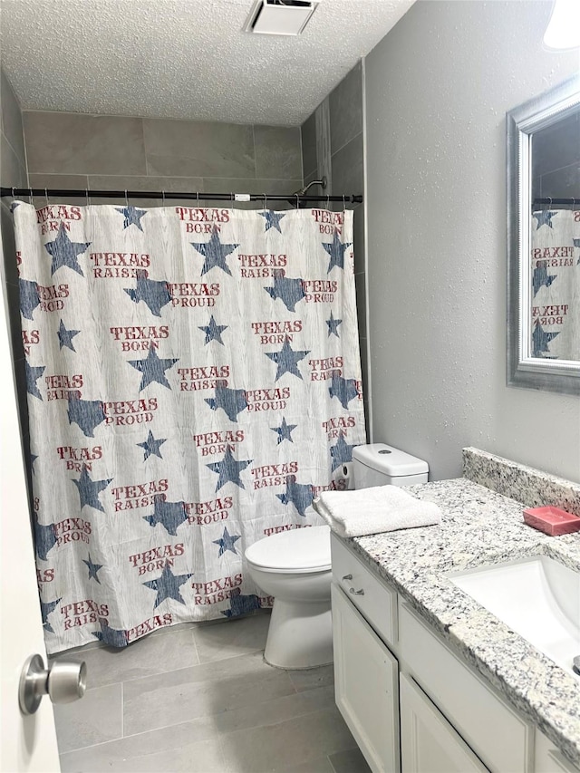 bathroom with curtained shower, vanity, a textured ceiling, and toilet