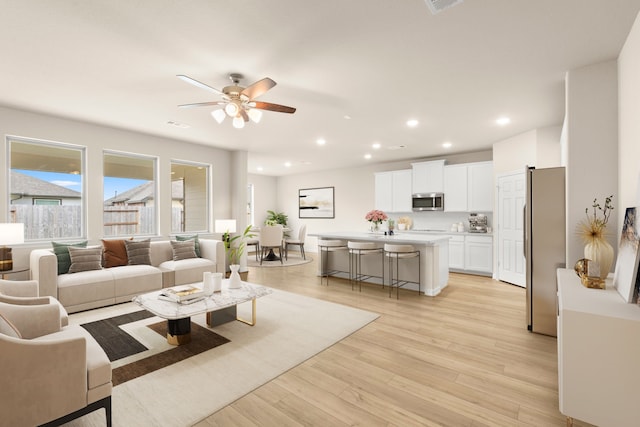 living room featuring ceiling fan and light hardwood / wood-style floors