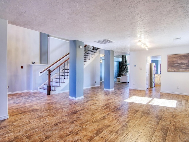 unfurnished living room featuring hardwood / wood-style floors and a textured ceiling