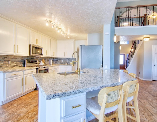 kitchen featuring white cabinetry, sink, light stone countertops, and stainless steel appliances