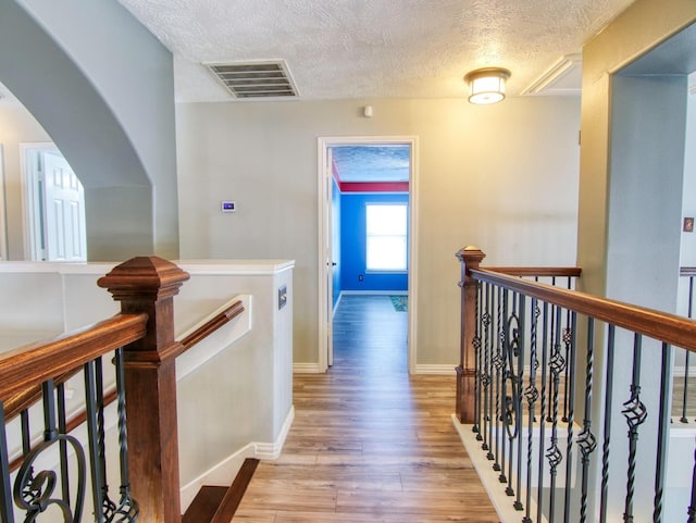 hall with light hardwood / wood-style floors and a textured ceiling