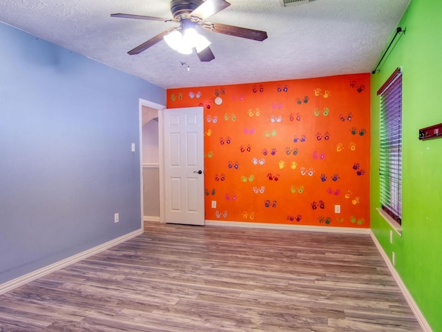 empty room featuring ceiling fan, a textured ceiling, and hardwood / wood-style flooring