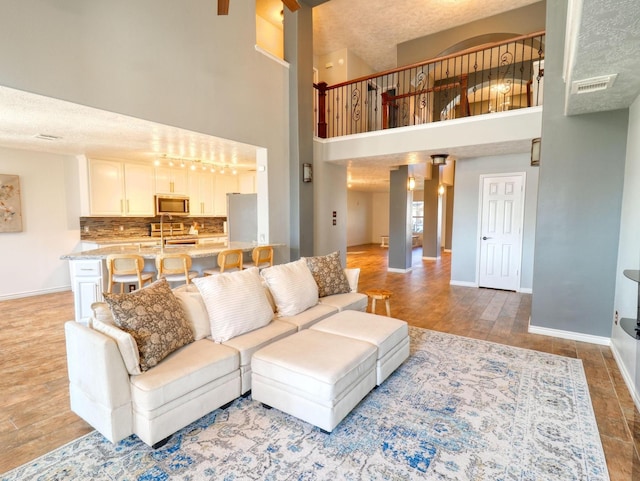 living room featuring sink, a towering ceiling, and a textured ceiling