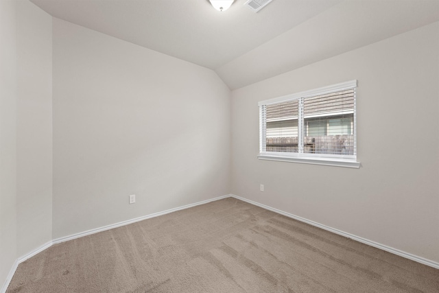 carpeted spare room featuring vaulted ceiling