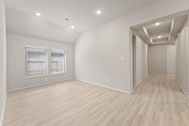 empty room featuring vaulted ceiling and light wood-type flooring