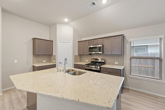 kitchen with a center island with sink, sink, lofted ceiling, and stainless steel appliances