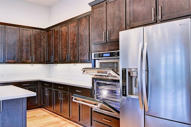 kitchen featuring light hardwood / wood-style floors, stainless steel fridge, dark brown cabinetry, and tasteful backsplash