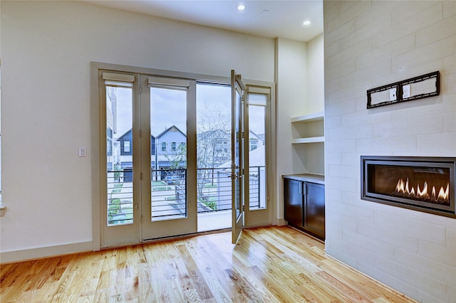 doorway featuring built in shelves, a fireplace, and light wood-type flooring