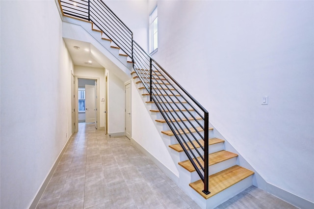 stairway featuring a towering ceiling