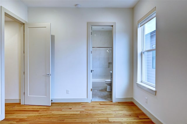 unfurnished bedroom with ensuite bath and light hardwood / wood-style floors