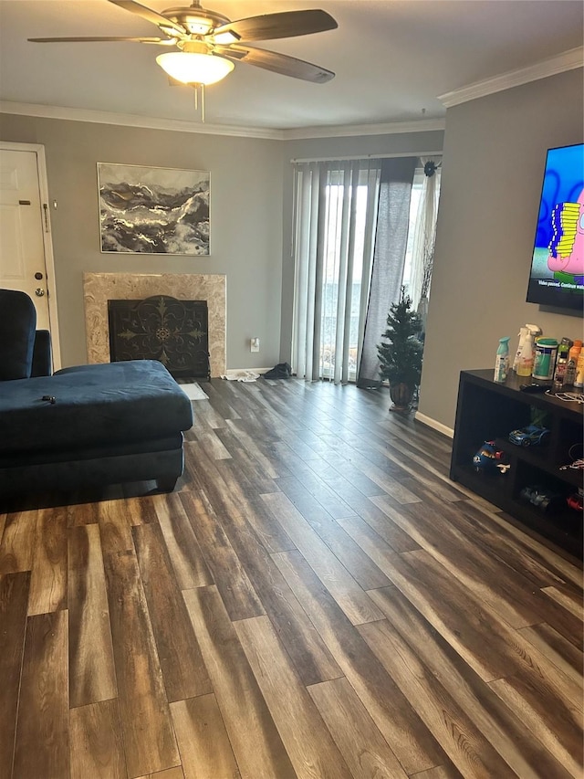 living room with a high end fireplace, dark hardwood / wood-style flooring, ceiling fan, and crown molding