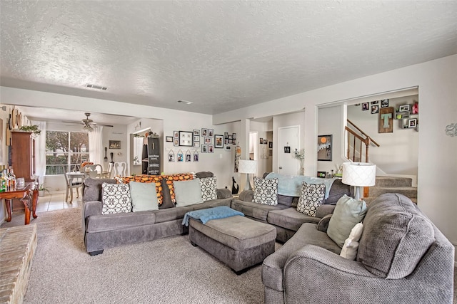 living room featuring a textured ceiling, carpet floors, and ceiling fan