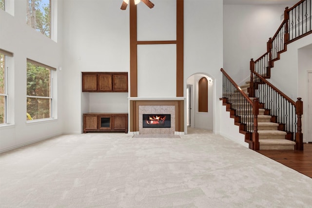 unfurnished living room featuring carpet, a high ceiling, and ceiling fan