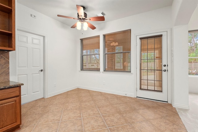 unfurnished dining area with ceiling fan and light tile patterned flooring