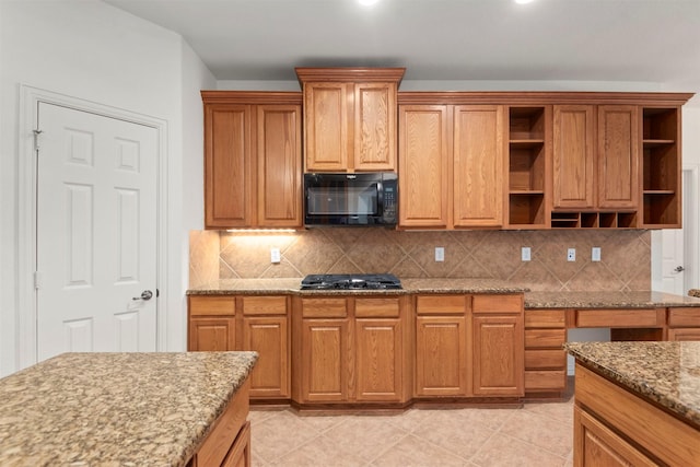 kitchen featuring decorative backsplash, light tile patterned floors, light stone countertops, and black appliances