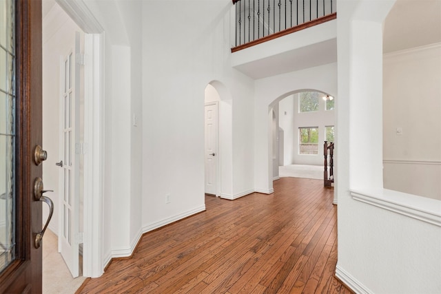 foyer with a towering ceiling, light wood-type flooring, and ornamental molding