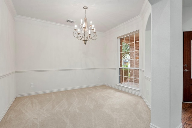 carpeted empty room featuring crown molding and a chandelier