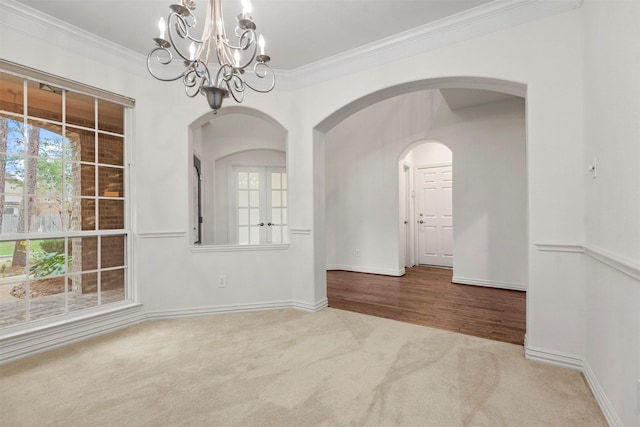 carpeted empty room featuring a chandelier and ornamental molding