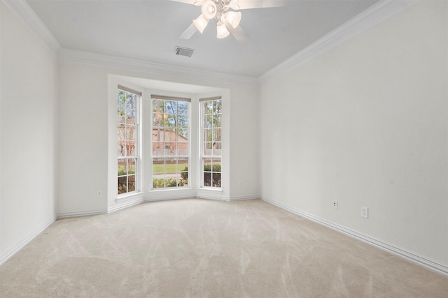 carpeted spare room with a wealth of natural light, crown molding, and ceiling fan