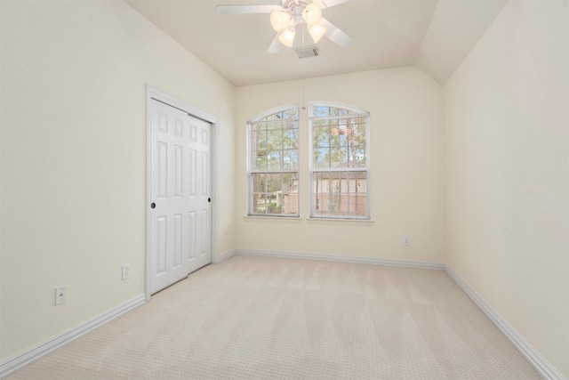 unfurnished bedroom featuring ceiling fan, vaulted ceiling, light colored carpet, and a closet