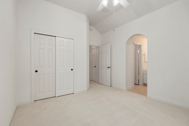 unfurnished bedroom with connected bathroom, ceiling fan, lofted ceiling, light carpet, and a closet