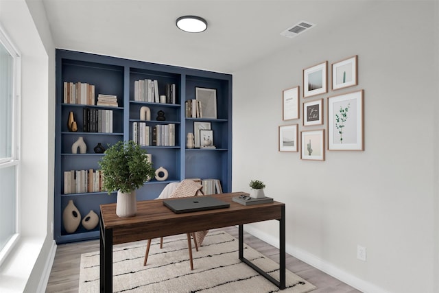 office with built in shelves and light wood-type flooring