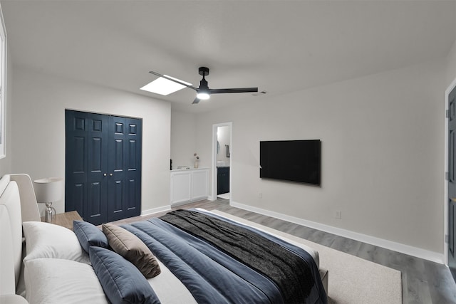 bedroom featuring a closet, connected bathroom, hardwood / wood-style flooring, and ceiling fan