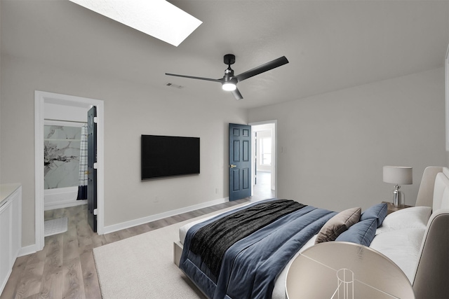 bedroom featuring ensuite bath, ceiling fan, light hardwood / wood-style floors, and a skylight