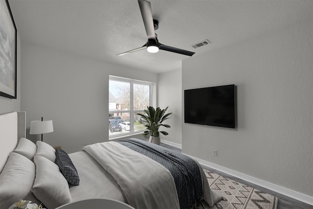 bedroom with a textured ceiling, hardwood / wood-style flooring, and ceiling fan