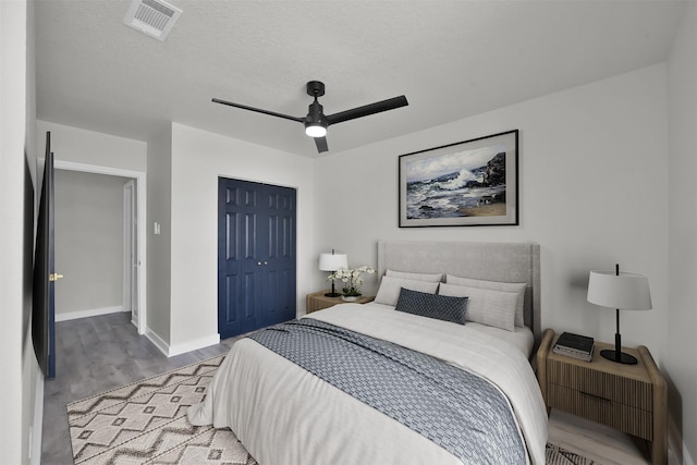 bedroom featuring hardwood / wood-style flooring, ceiling fan, a textured ceiling, and a closet