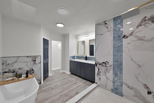 bathroom with hardwood / wood-style flooring, vanity, a tub to relax in, and tile walls