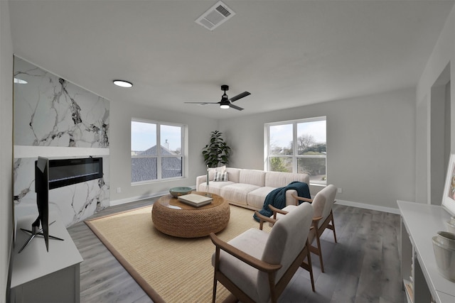 living room with a fireplace, ceiling fan, and dark wood-type flooring