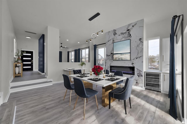 dining space with a fireplace, hardwood / wood-style floors, beverage cooler, and ceiling fan