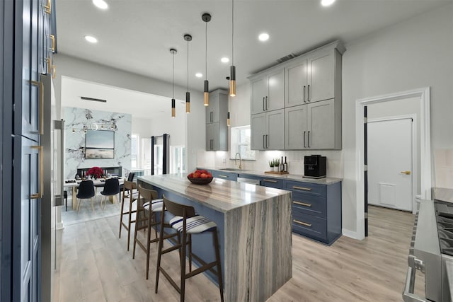 kitchen featuring sink, hanging light fixtures, a breakfast bar area, a kitchen island, and light wood-type flooring