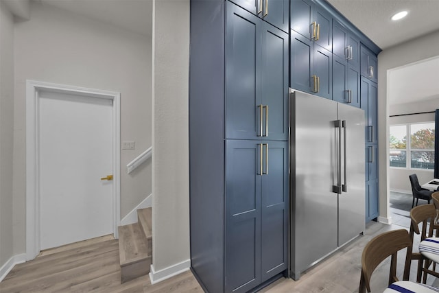 kitchen with blue cabinetry, a textured ceiling, light hardwood / wood-style flooring, and high quality fridge