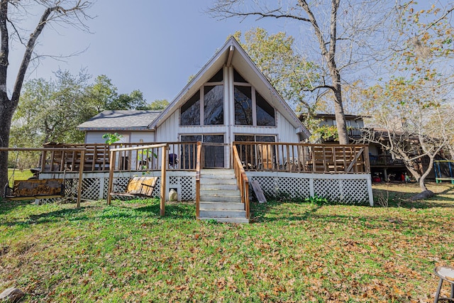 back of property featuring a deck and a lawn