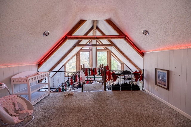 interior space featuring a textured ceiling, carpet floors, wooden walls, and lofted ceiling