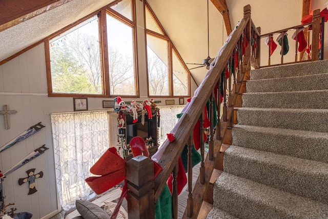 stairs featuring vaulted ceiling with beams, wood walls, and ceiling fan