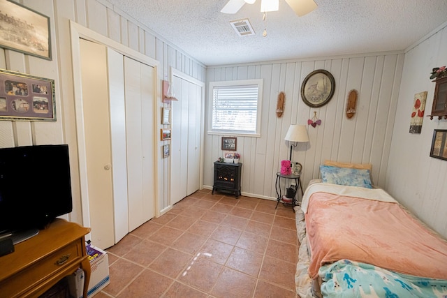 bedroom featuring ceiling fan, light tile patterned flooring, and a textured ceiling