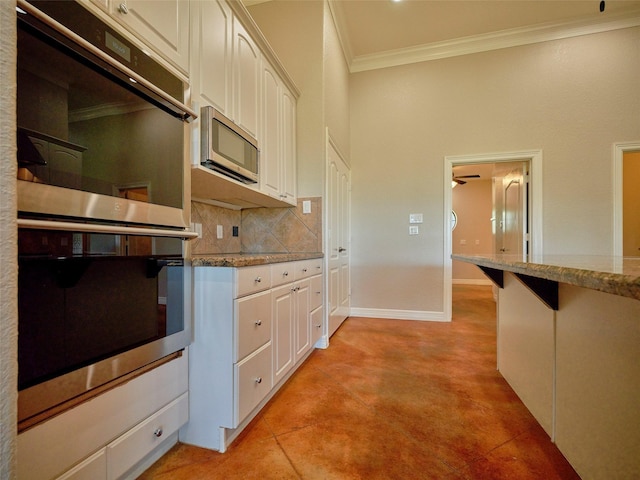 kitchen featuring double oven, backsplash, white cabinetry, and light stone counters