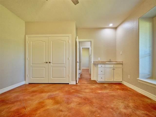 unfurnished bedroom with a closet, ceiling fan, and sink