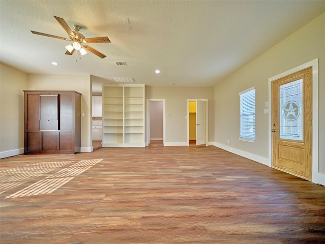 unfurnished living room featuring a textured ceiling, light hardwood / wood-style floors, and ceiling fan