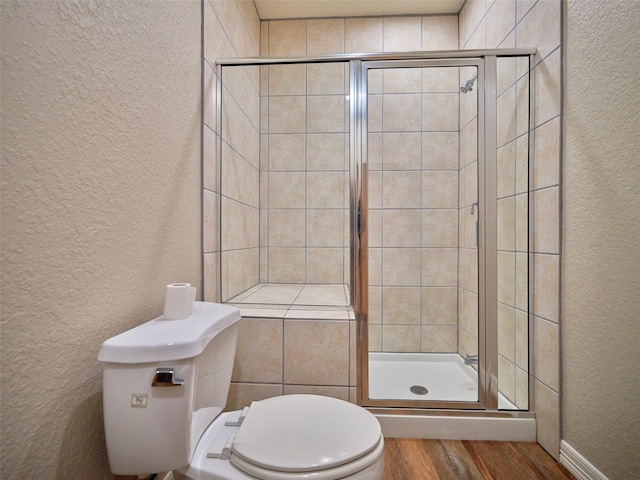 bathroom with toilet, wood-type flooring, and a shower with door