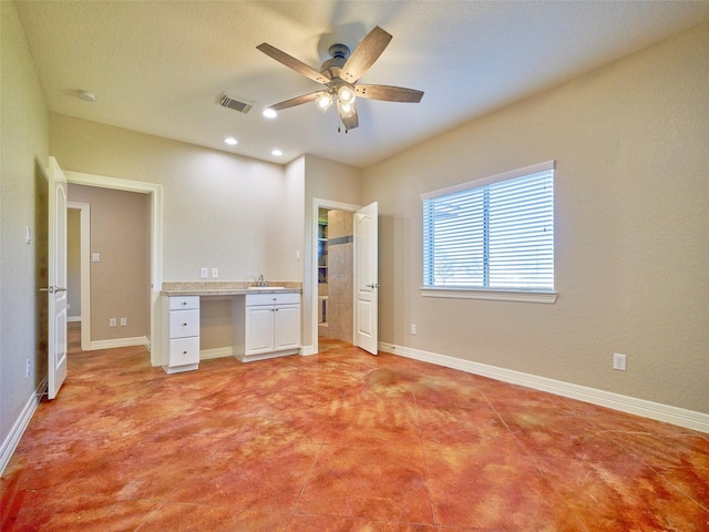 unfurnished bedroom featuring ceiling fan, built in desk, and sink