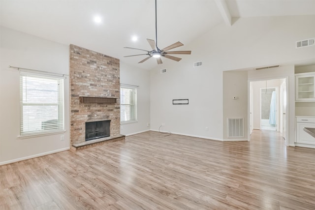 unfurnished living room featuring beam ceiling, ceiling fan, a fireplace, and plenty of natural light