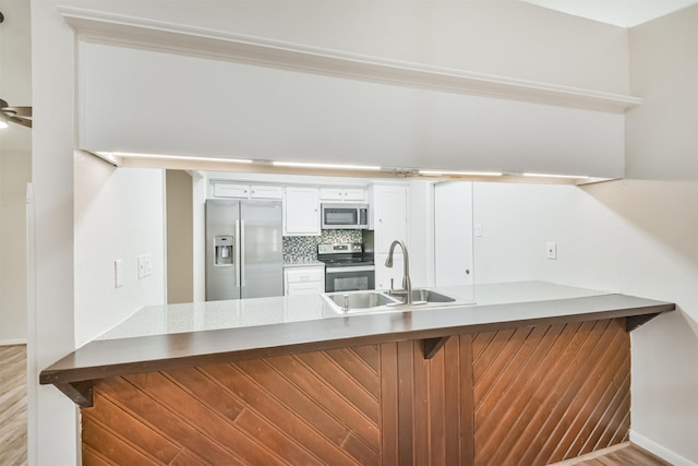 kitchen with decorative backsplash, a breakfast bar, stainless steel appliances, sink, and white cabinetry